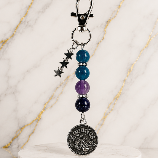 Keychain with beads and a zodiac charm on a marble stand